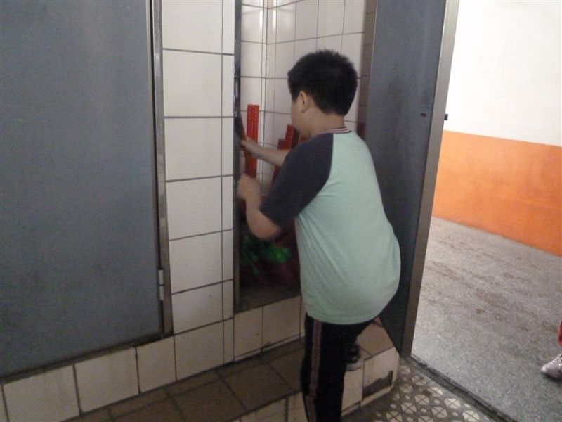 第四棟二樓廁所內認真整理掃具的小朋友